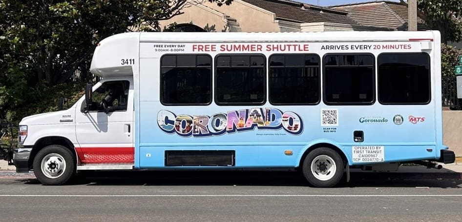 A white and light blue shuttle bus labeled “Coronado” offers a free summer shuttle service, arriving every 20 minutes. The bus also displays schedules, logos, and city information along its side.